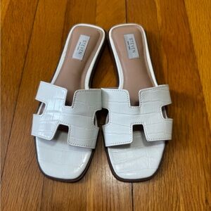 White crocodile embossed slide sandals are the Steven Hanna